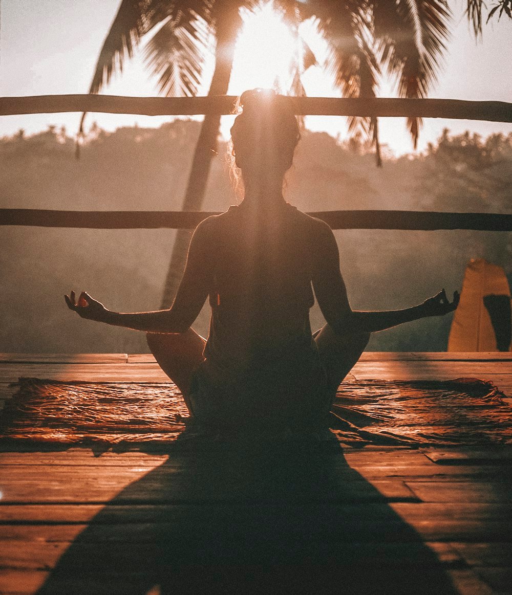 Silueta de una persona meditando al atardecer (imagen de stock)